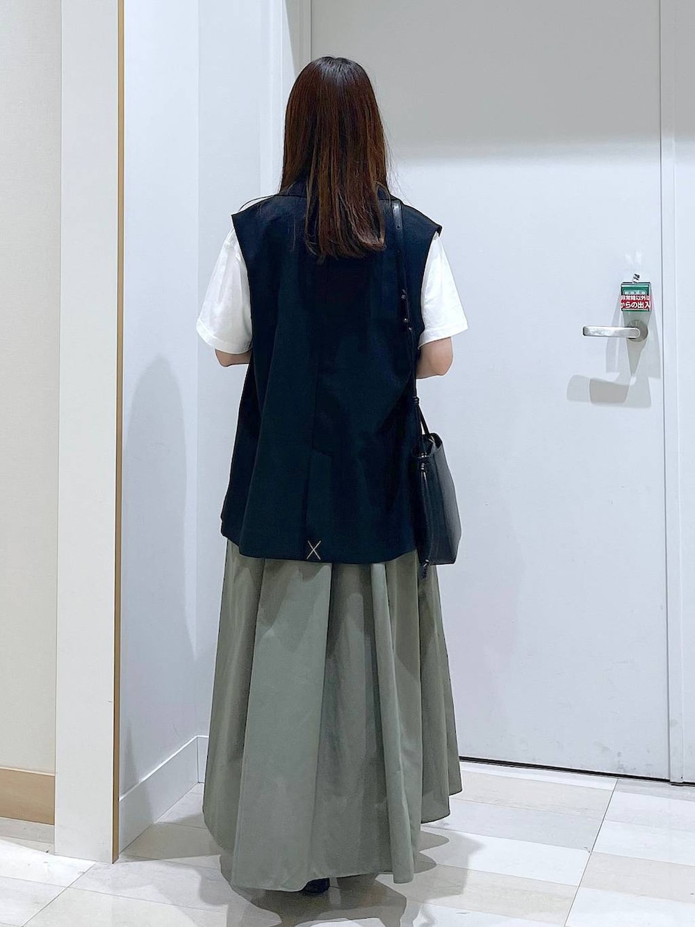 ブラック系のバレエシューズ、ブラック系のベスト、ホワイト系のTシャツ/カットソーを着用したレディースの春コーディネートの3枚目の写真