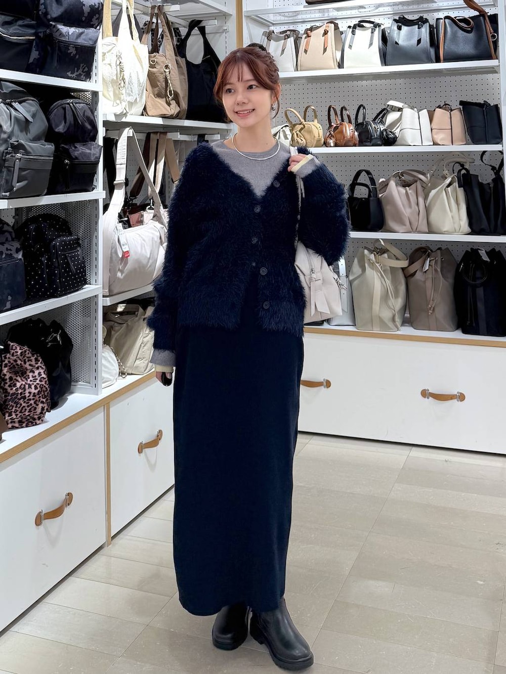 ブラック系のダウンジャケット/コート、ホワイト系のボストンバッグ、ブルー系のワンピースを着用したレディースの冬コーディネートの4枚目の写真