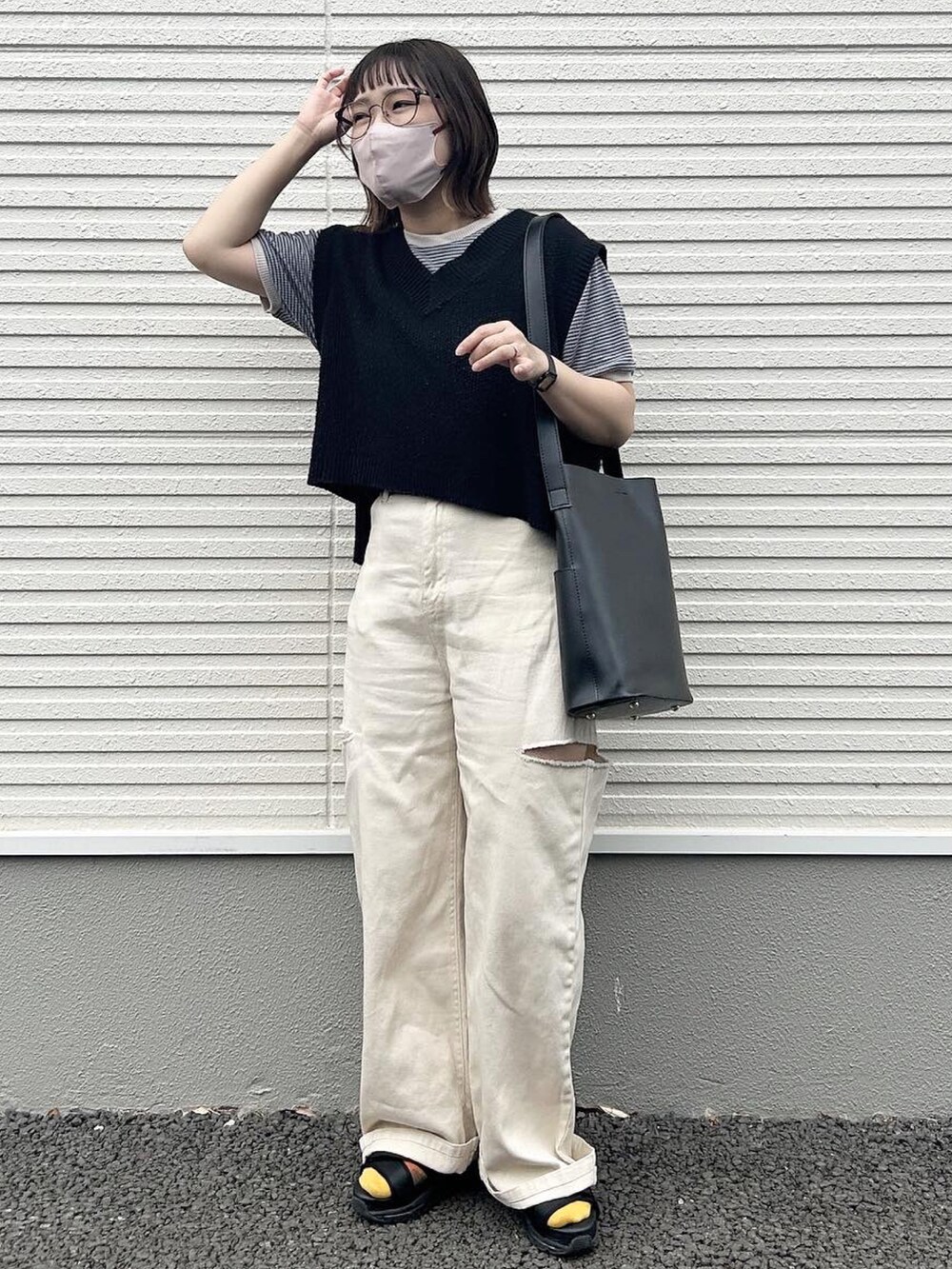 ブラック系のトートバッグ、ブラック系のベスト、ホワイト系のデニムパンツを着用したレディースの夏コーディネートの3枚目の写真