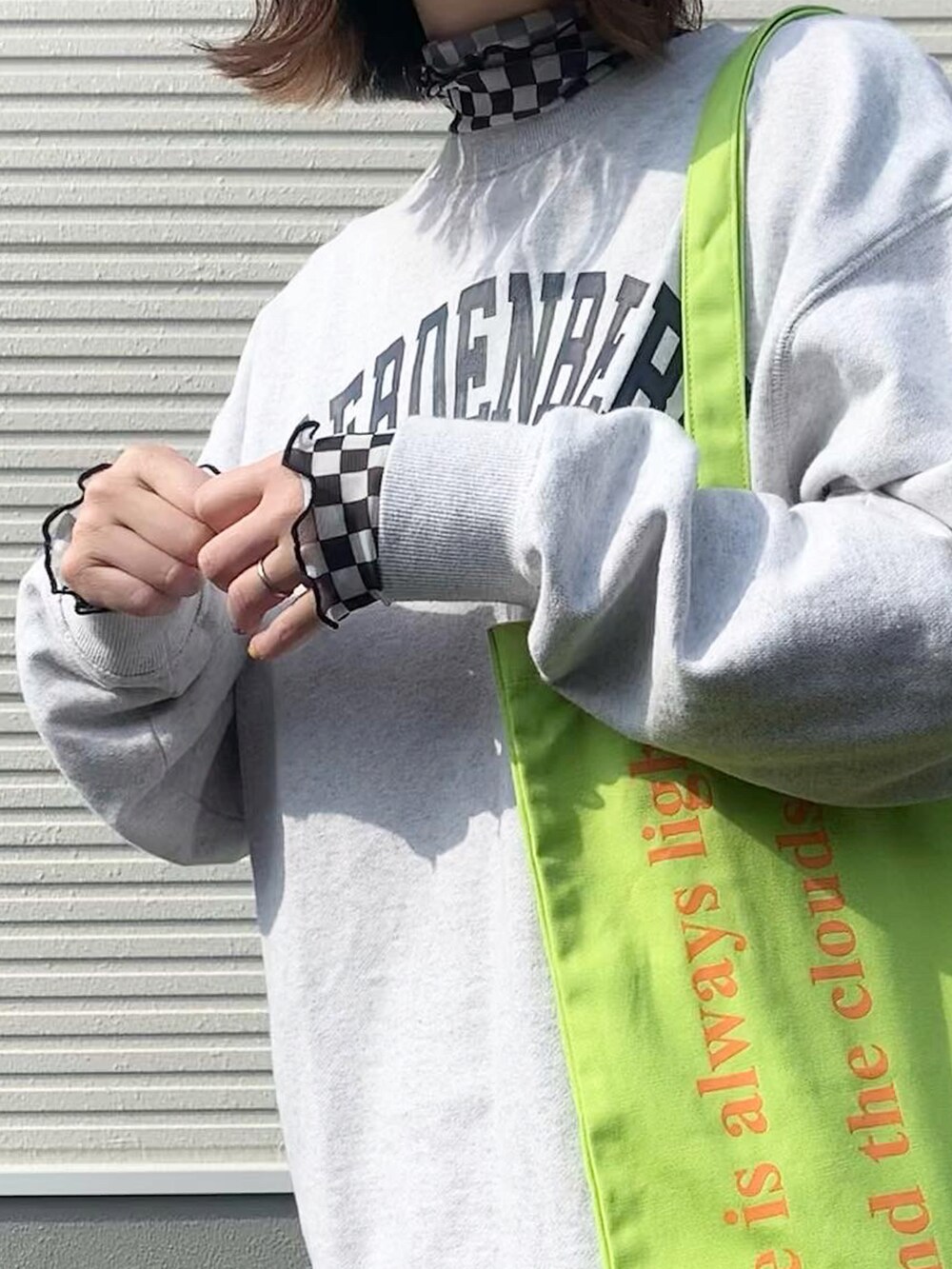 グレー系のスウェット、グリーン系のトートバッグ、ブラック系のスカートを着用したレディースの春コーディネートの2枚目の写真