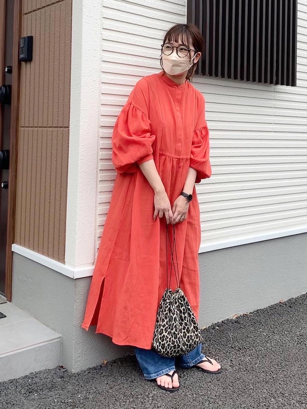 オレンジ系のワンピース、その他のショルダーバッグ、ブルー系のデニムパンツを着用したレディースの春コーディネートの2枚目の写真