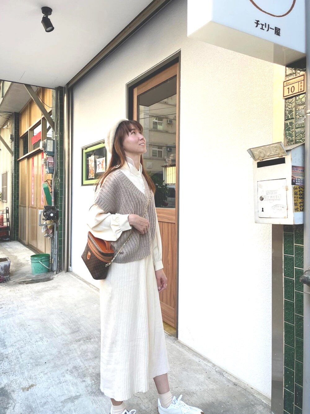 ベージュ系のベスト、ベージュ系のシューズ、ブラウン系のバッグを着用したレディースの春コーディネートの2枚目の写真