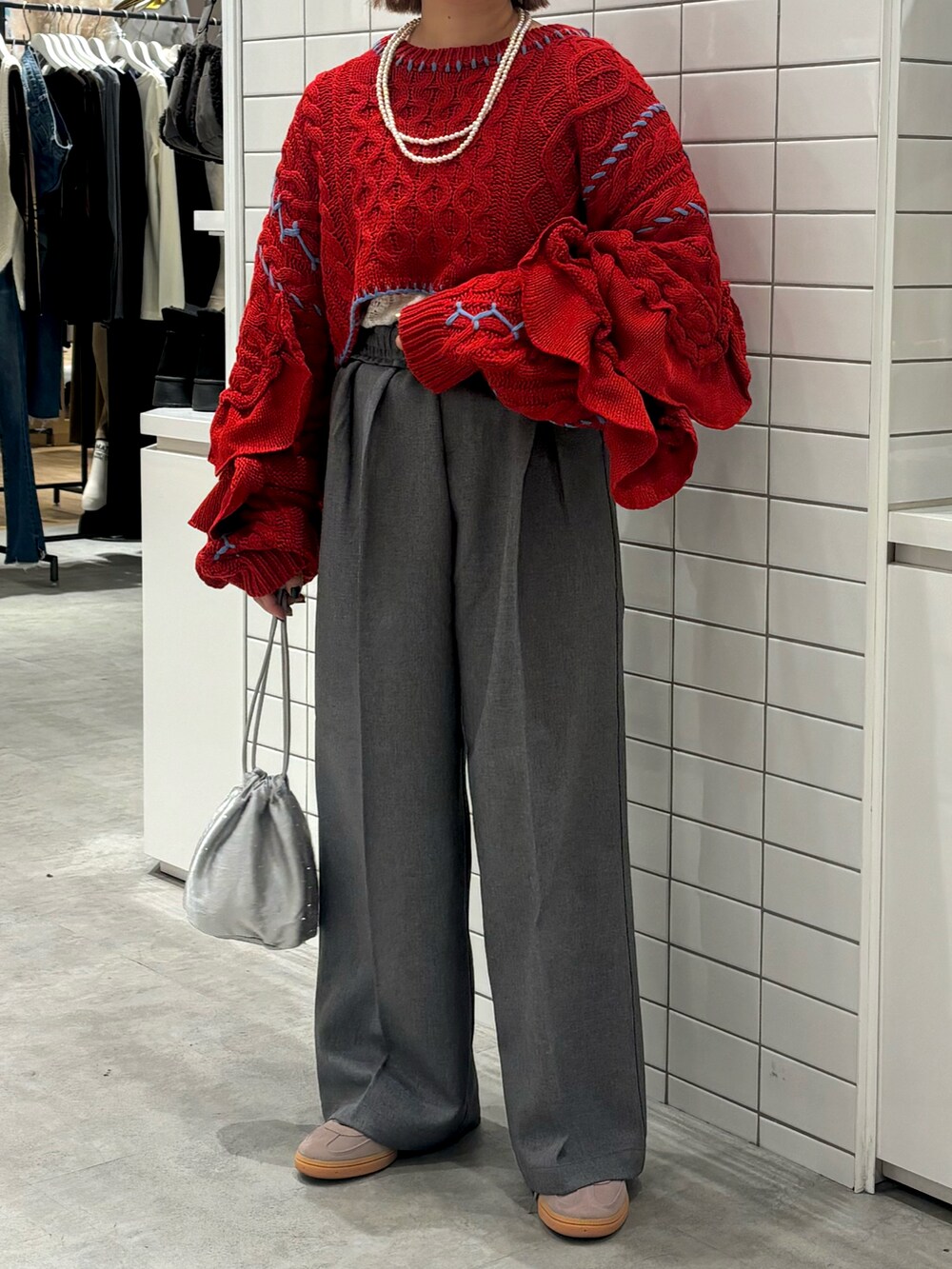 レッド系のニット/セーター、グレー系のスラックス、シルバー系のトートバッグを着用したレディースの冬コーディネートの2枚目の写真