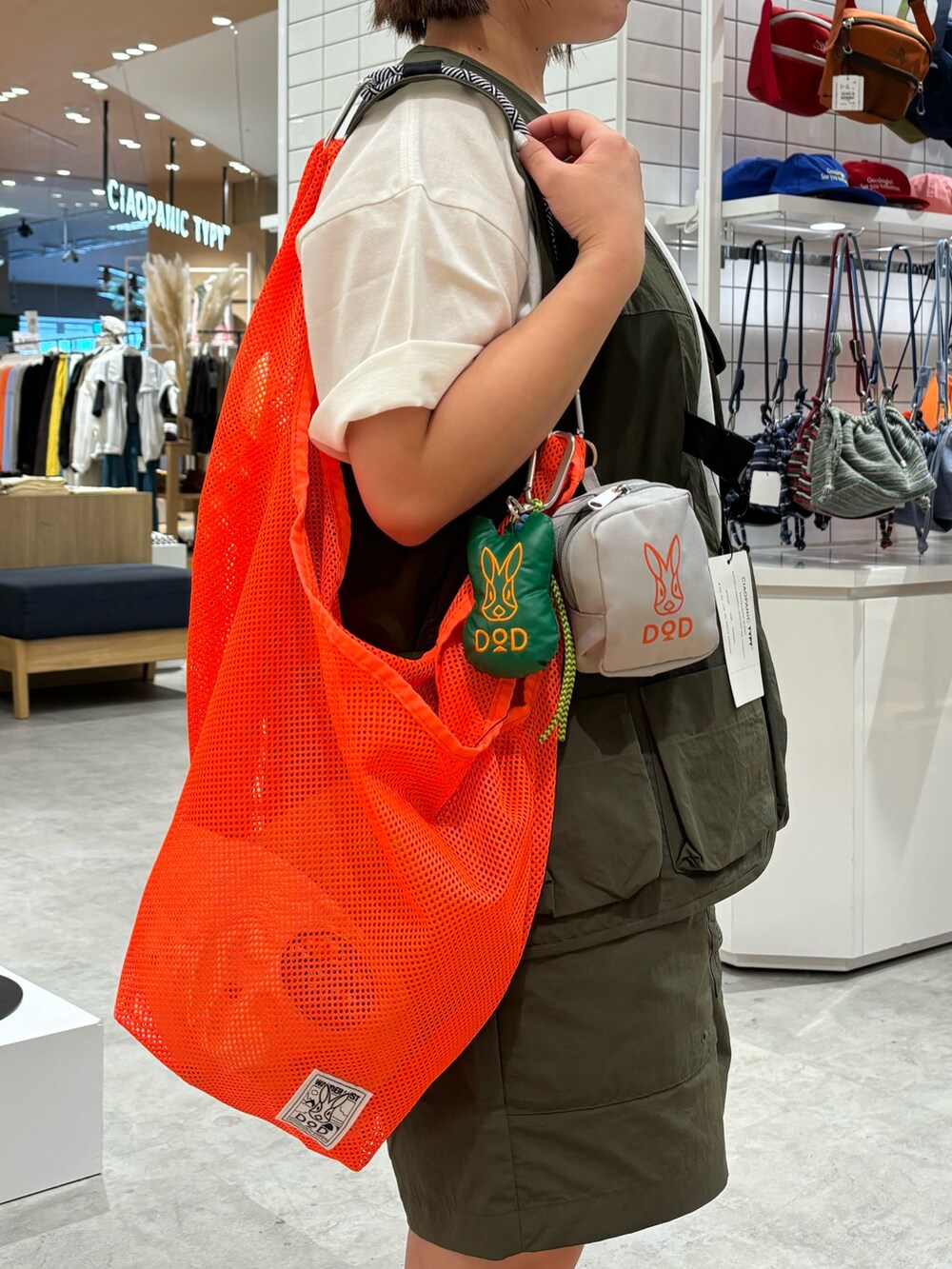 ホワイト系のTシャツ/カットソー、オレンジ系のトートバッグ、グリーン系のベストを着用したレディースの春コーディネートの3枚目の写真