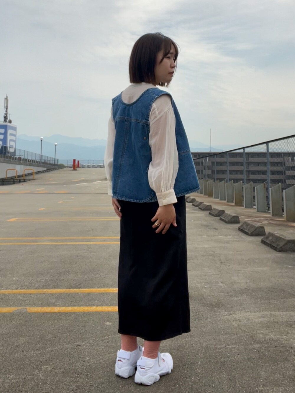 ホワイト系のシャツ/ブラウス、ブルー系のベスト、ブラック系のスカートを着用したレディースの春コーディネートの4枚目の写真