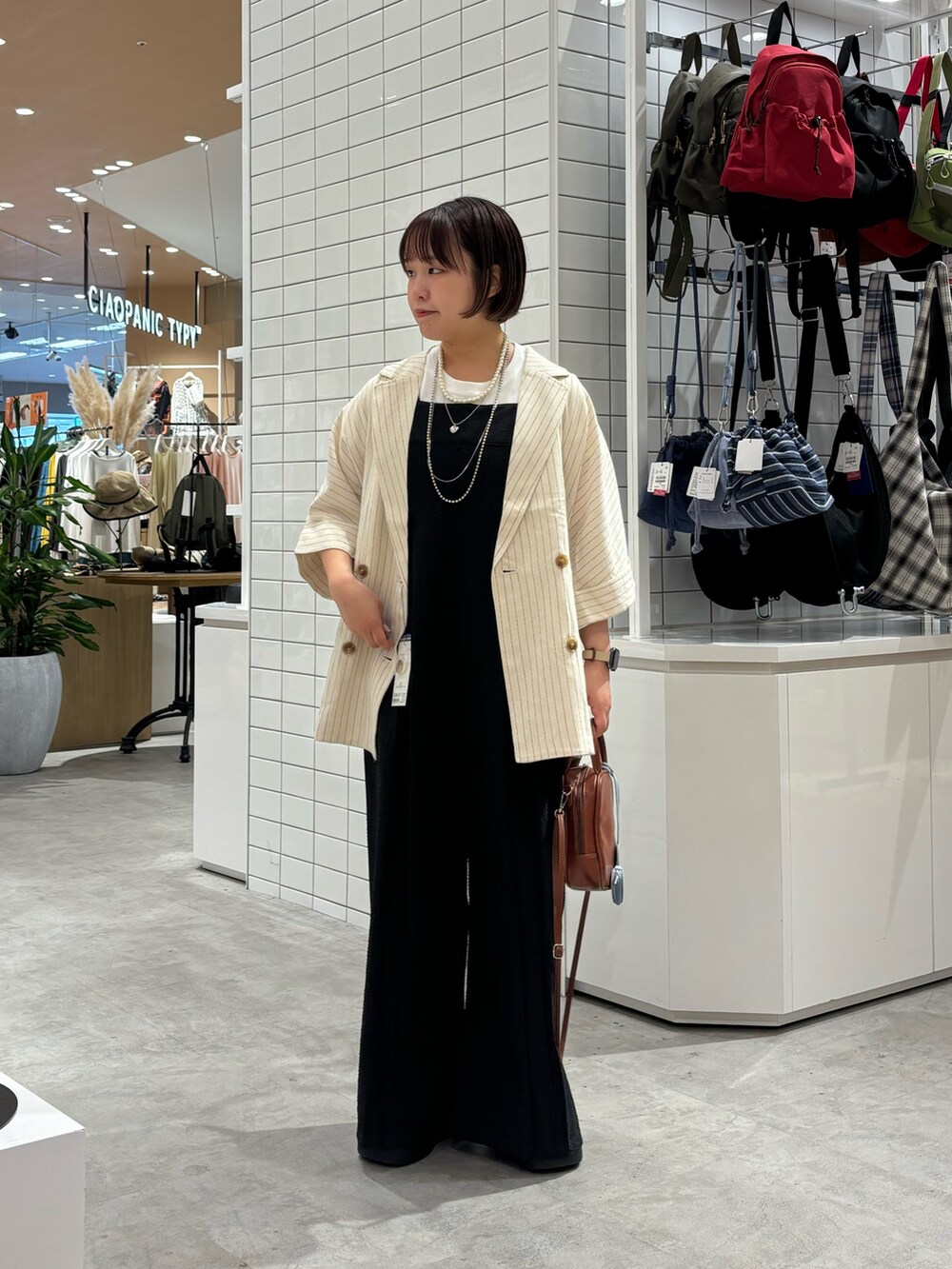 ブラック系のサロペット/オーバーオール、ホワイト系のテーラードジャケット、ブラック系のサンダルを着用したレディースの夏コーディネートの2枚目の写真