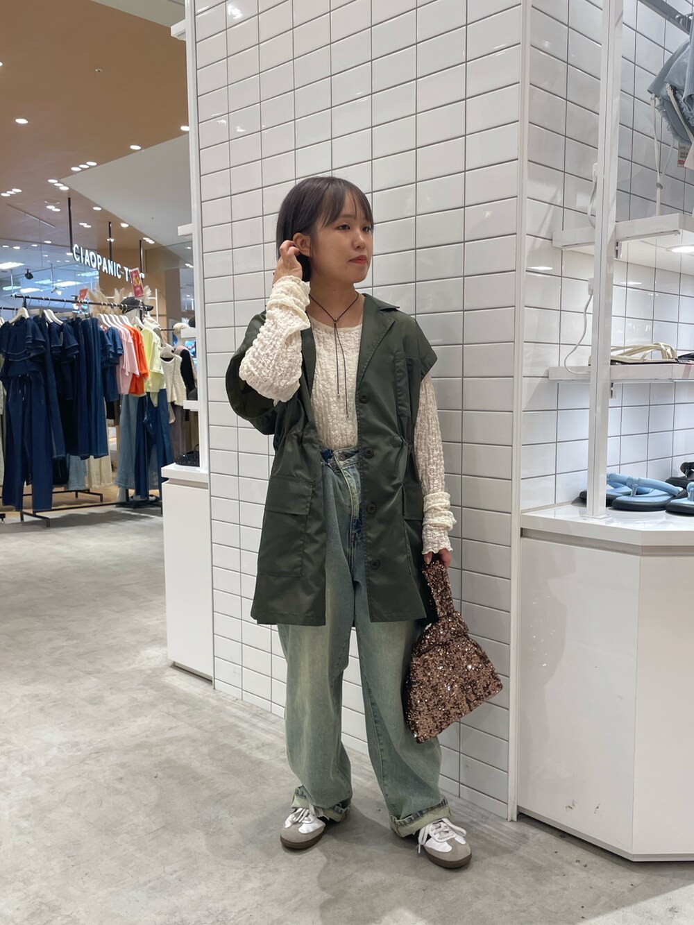 ホワイト系のTシャツ/カットソー、ブルー系のデニムパンツ、ブラウン系のハンドバッグを着用したレディースの秋コーディネートの2枚目の写真