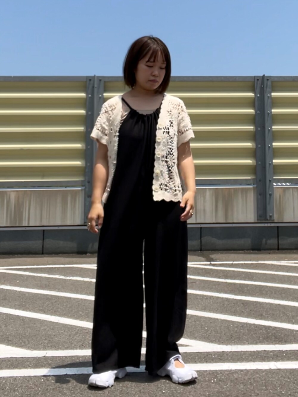 ホワイト系のキャミソール、ブラック系のサロペット/オーバーオール、ホワイト系のカーディガン/ボレロを着用したレディースの夏コーディネートの2枚目の写真