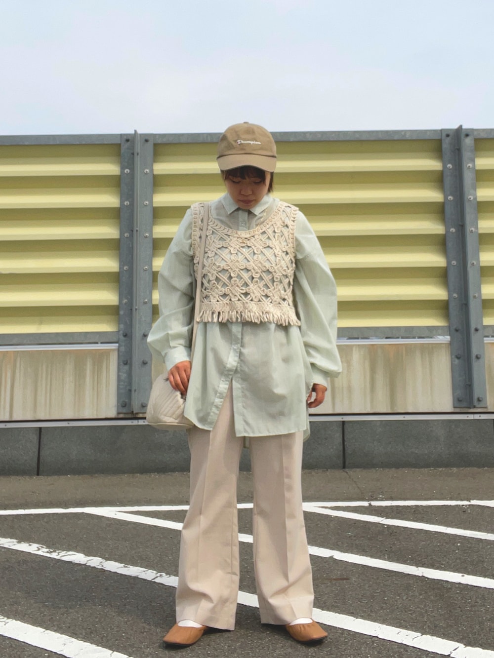 ベージュ系のスラックス、ベージュ系のベスト、ホワイト系のショルダーバッグを着用したレディースの春コーディネートの2枚目の写真