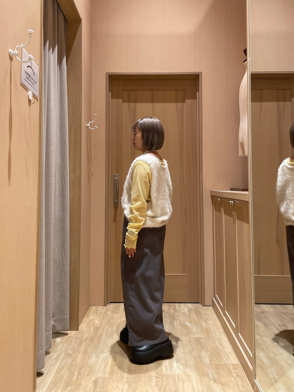 ブラック系のブーツ、グレー系のスカート、ホワイト系のベストを着用したレディースの秋コーディネートの2枚目の写真