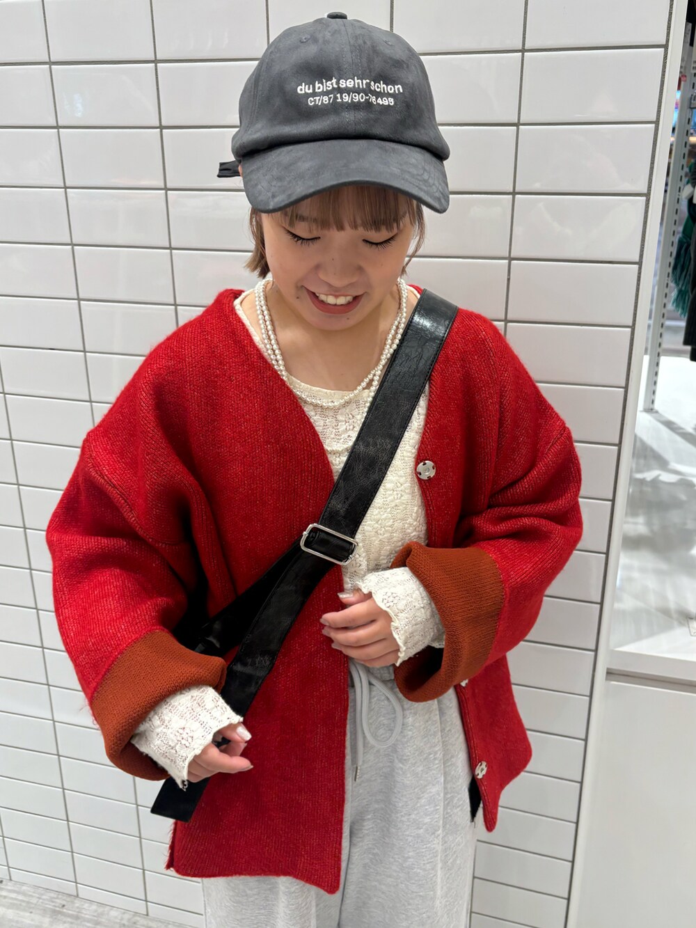 ホワイト系のTシャツ/カットソー、レッド系のカーディガン/ボレロ、グレー系のスウェットパンツを着用したレディースの冬コーディネートの3枚目の写真