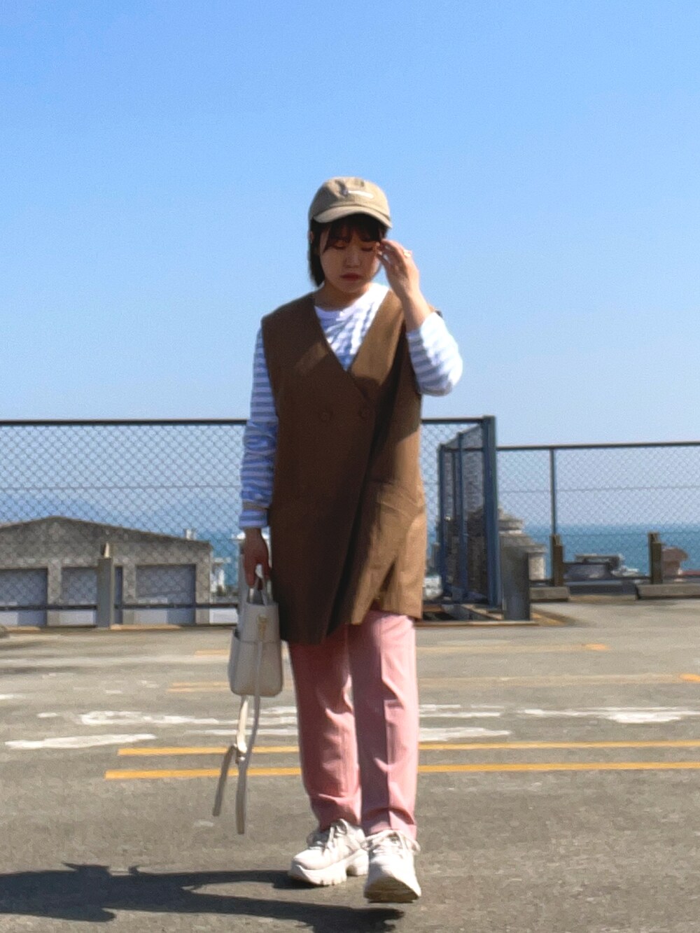 ブルー系のTシャツ/カットソー、ブラウン系のベスト、ホワイト系のショルダーバッグを着用したレディースの春コーディネートの4枚目の写真