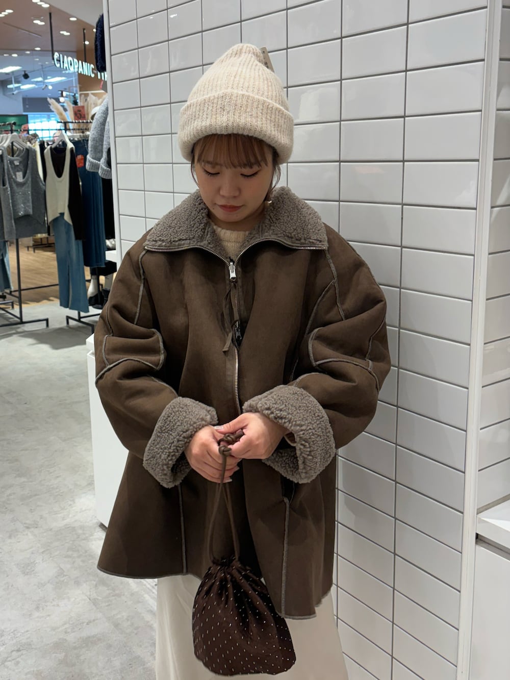 ベージュ系のニット/セーター、ホワイト系のスカート、ブラウン系のムートンコートを着用したレディースの冬コーディネートの3枚目の写真