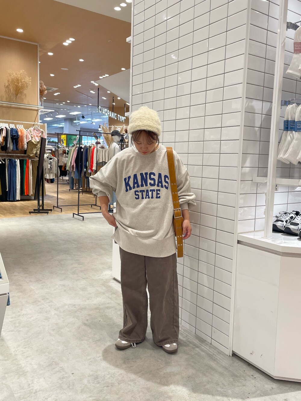ブラウン系のデニムパンツ、ホワイト系のスウェット、ブラウン系のショルダーバッグを着用したレディースの秋コーディネートの3枚目の写真