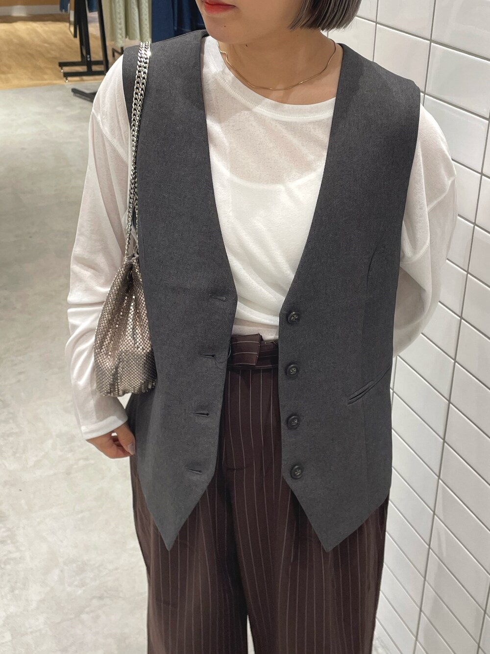 ゴールド系のショルダーバッグ、ブラウン系のスラックス、ホワイト系のTシャツ/カットソーを着用したレディースの秋コーディネートの4枚目の写真