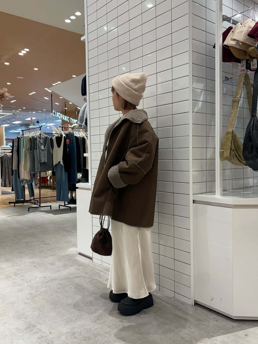 ベージュ系のニット/セーター、ホワイト系のスカート、ブラウン系のムートンコートを着用したレディースの冬コーディネートの2枚目の写真