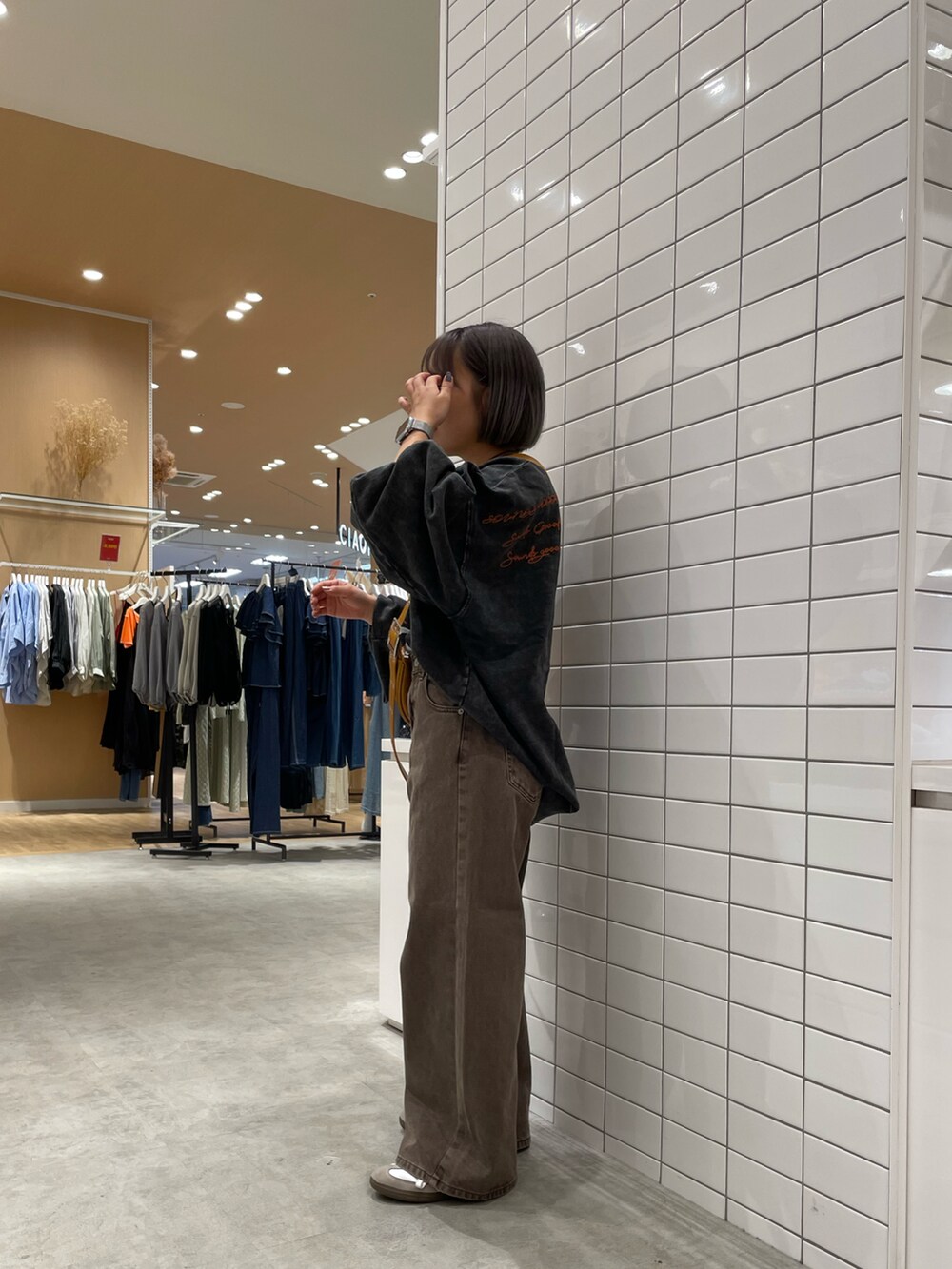 ブラック系のスウェット、ブラウン系のショルダーバッグ、ブラウン系のデニムパンツを着用したレディースの秋コーディネートの2枚目の写真