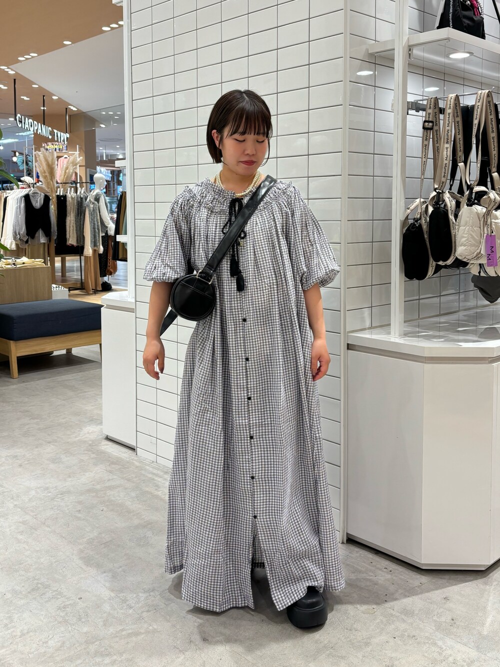 ホワイト系のタンクトップ、ブラック系のショルダーバッグ、ブラック系のワンピースを着用したレディースの春コーディネートの2枚目の写真