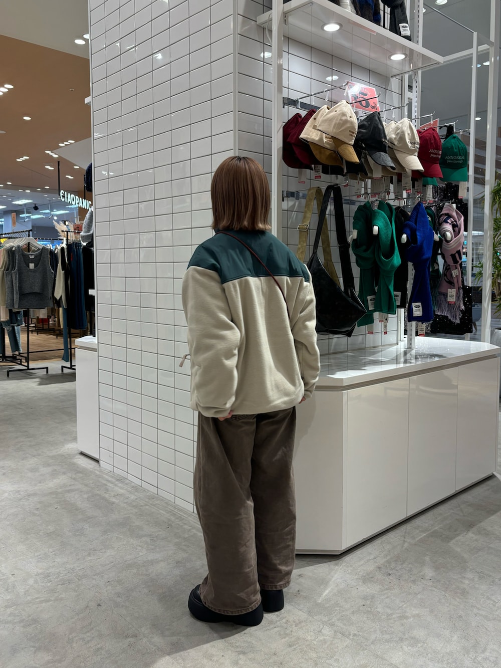 ホワイト系のブルゾン、ブラック系のショルダーバッグ、ブラウン系のデニムパンツを着用したレディースの春コーディネートの2枚目の写真