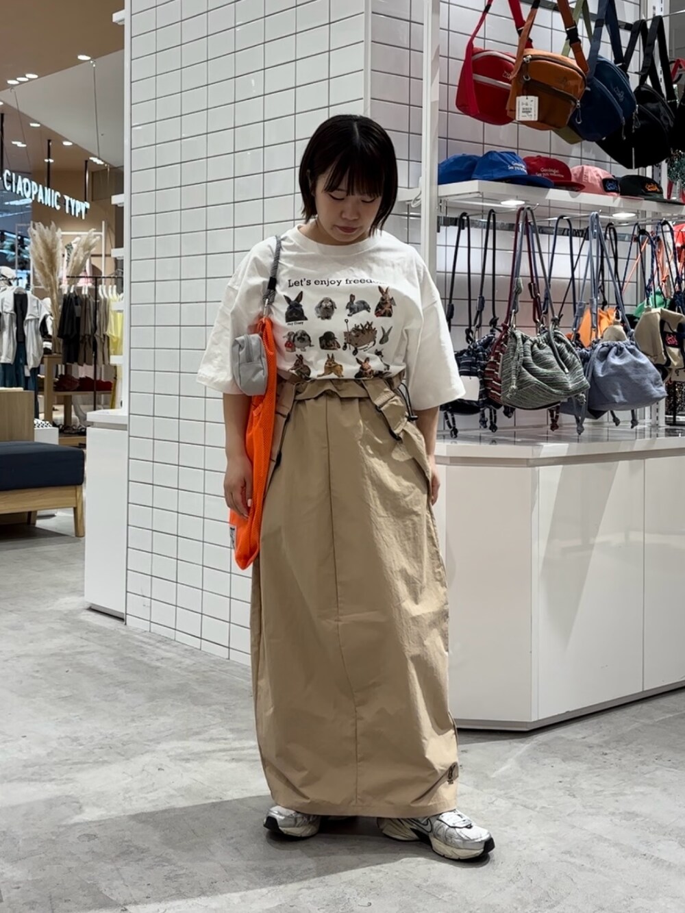 ホワイト系のTシャツ/カットソー、ベージュ系のスカート、オレンジ系のトートバッグを着用したレディースの春コーディネートの2枚目の写真