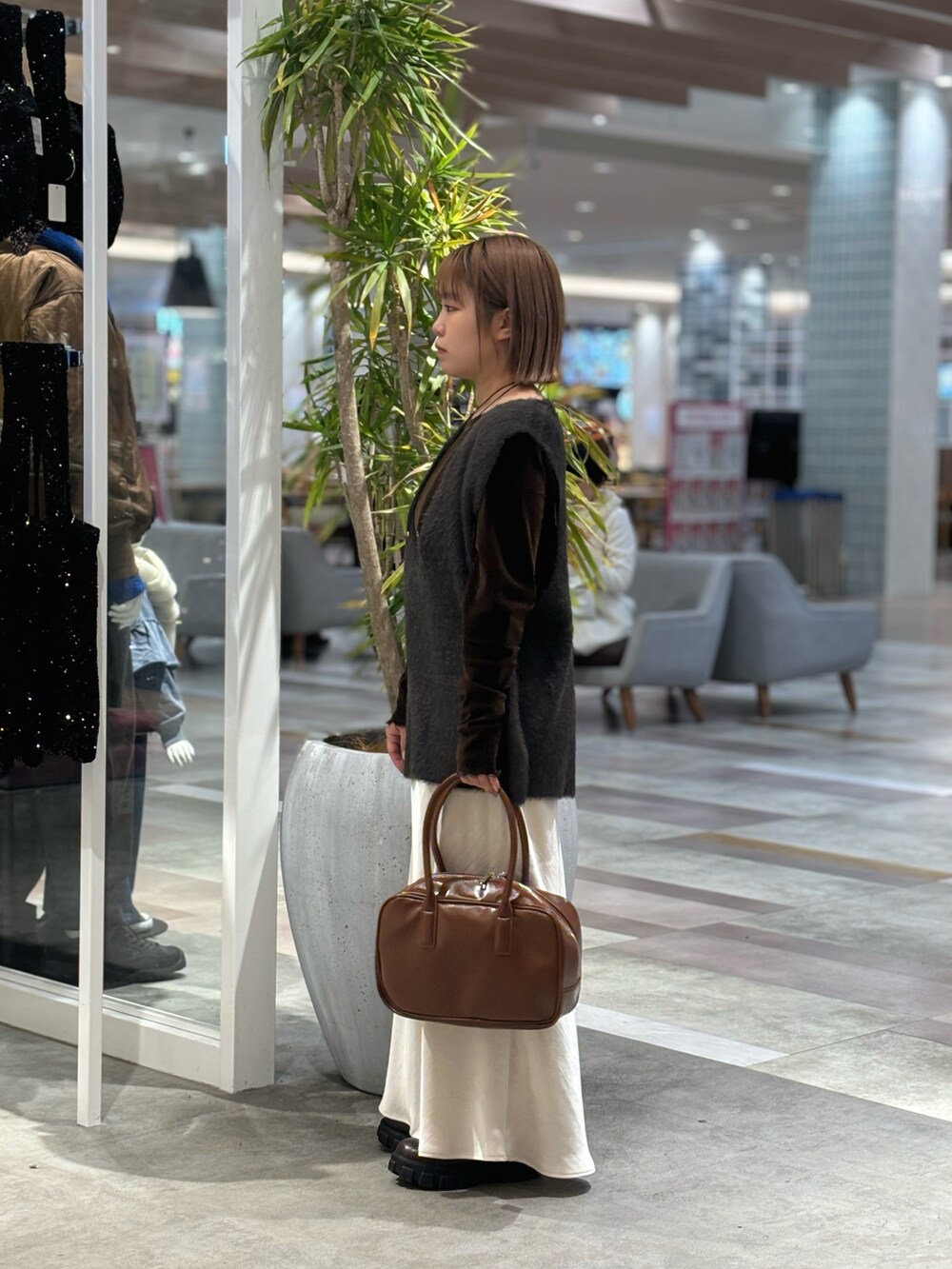 ブラウン系のボストンバッグ、ホワイト系のスカート、グレー系のベストを着用したレディースの冬コーディネートの3枚目の写真