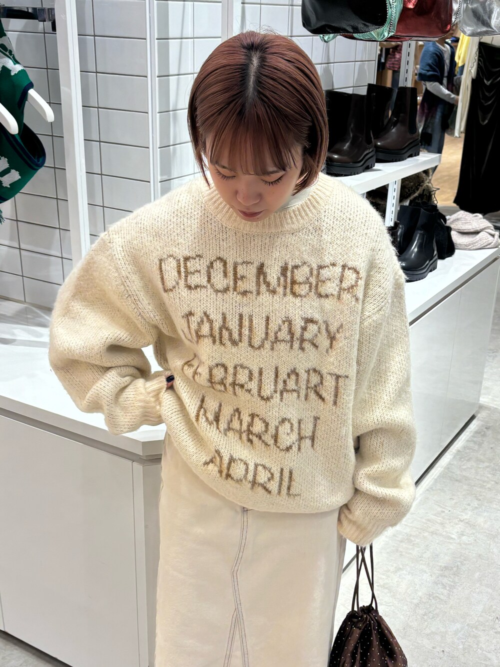 ベージュ系のニット/セーター、ホワイト系のデニムスカート、ブラウン系のショルダーバッグを着用したレディースの秋コーディネートの3枚目の写真