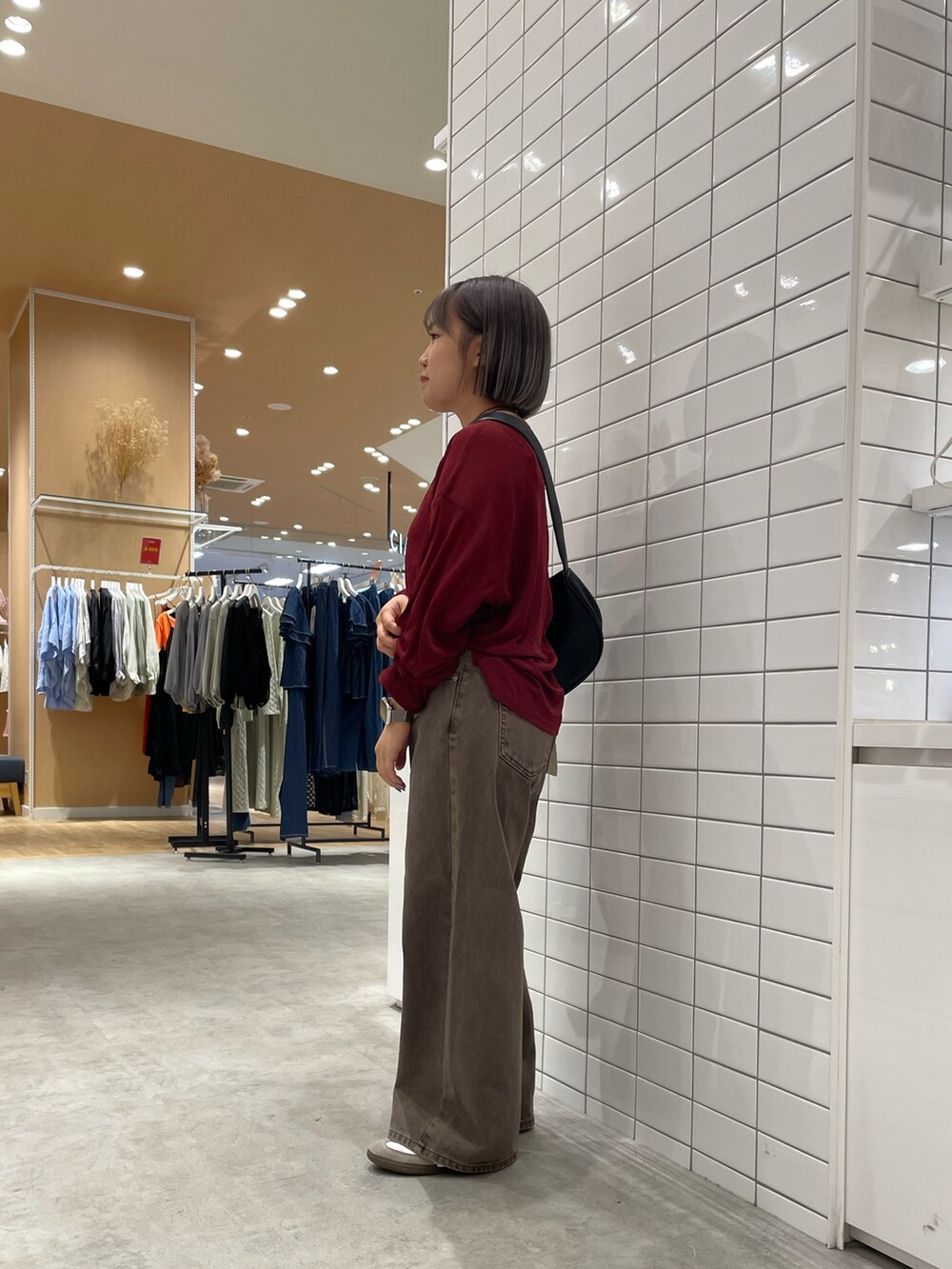 ブラウン系のデニムパンツ、レッド系のTシャツ/カットソー、ブラック系のショルダーバッグを着用したレディースの秋コーディネートの2枚目の写真