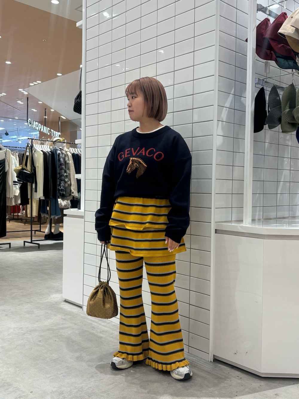 イエロー系のスカート、イエロー系のその他パンツ、グリーン系のショルダーバッグを着用したレディースの冬コーディネートの2枚目の写真