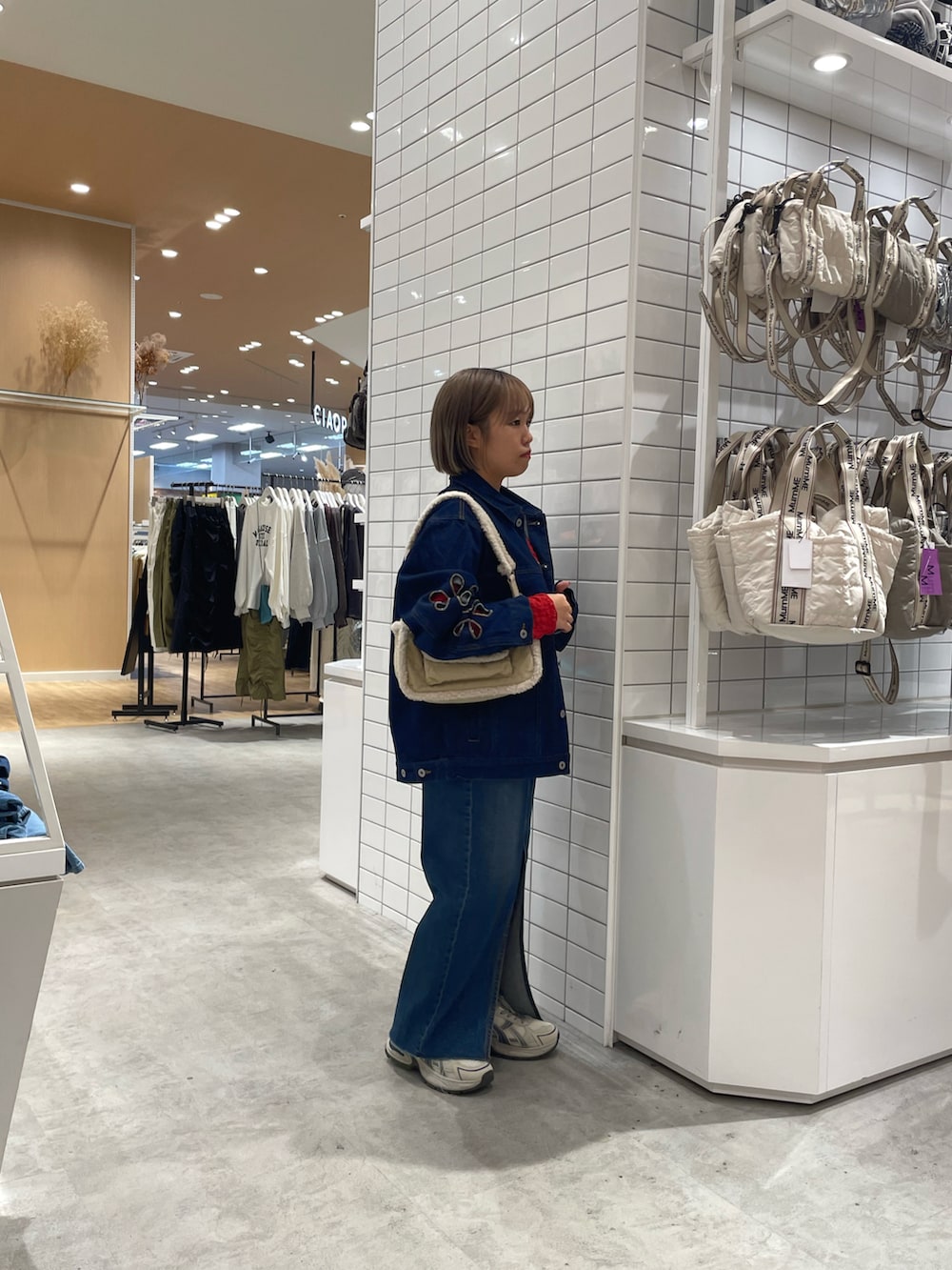 ブルー系のデニムジャケット、ブルー系のデニムスカート、ホワイト系のスニーカーを着用したレディースの秋コーディネートの3枚目の写真