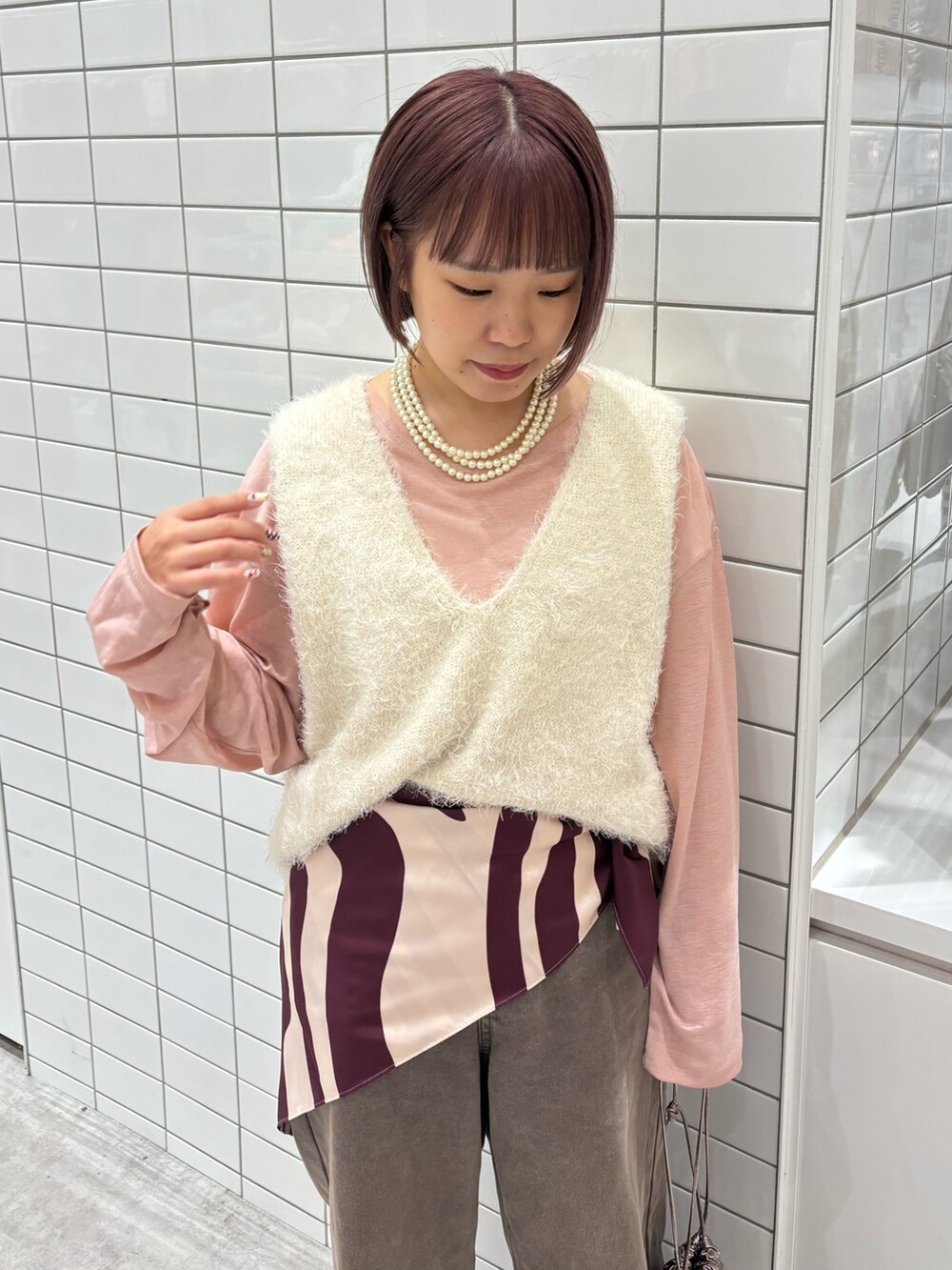 ホワイト系のベスト、ブラウン系のデニムパンツ、ベージュ系のトートバッグを着用したレディースの秋コーディネートの3枚目の写真