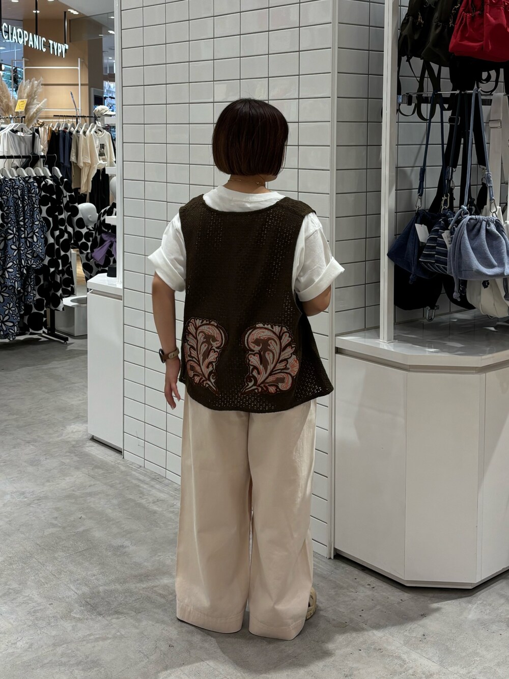 ホワイト系のデニムパンツ、ホワイト系のTシャツ/カットソー、ブラウン系のベストを着用したレディースの夏コーディネートの2枚目の写真