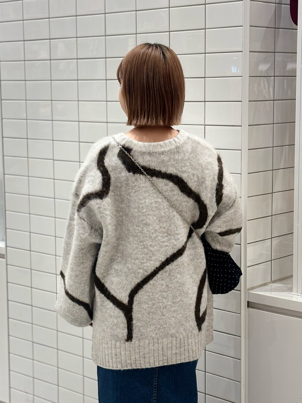 ホワイト系のニット/セーター、ブルー系のデニムスカート、ブラック系のブーツを着用したレディースの冬コーディネートの4枚目の写真