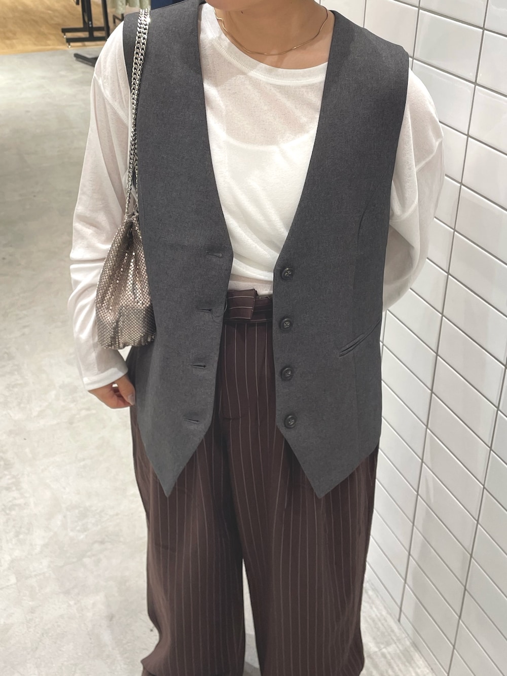 ホワイト系のTシャツ/カットソー、グレー系のベスト、ブラウン系のスラックスを着用したレディースの秋コーディネートの4枚目の写真