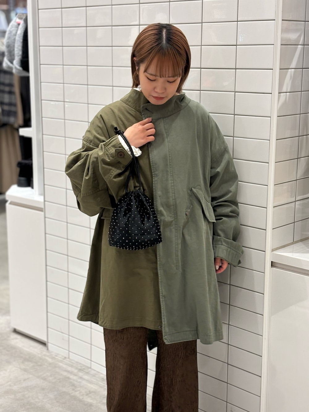 ブラック系のショルダーバッグ、ベージュ系のニット/セーター、グリーン系のモッズコートを着用したレディースの冬コーディネートの4枚目の写真