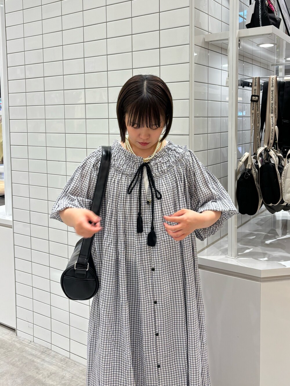 ホワイト系のタンクトップ、ブラック系のショルダーバッグ、ブラック系のワンピースを着用したレディースの春コーディネートの4枚目の写真