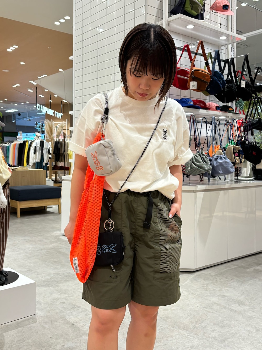 オレンジ系のトートバッグ、ホワイト系のTシャツ/カットソー、グリーン系のその他パンツを着用したレディースの春コーディネートの5枚目の写真