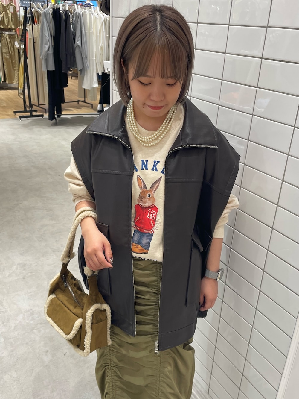 ホワイト系のスウェット、ブラウン系のライダースジャケット、ブラウン系のショルダーバッグを着用したレディースの秋コーディネートの4枚目の写真