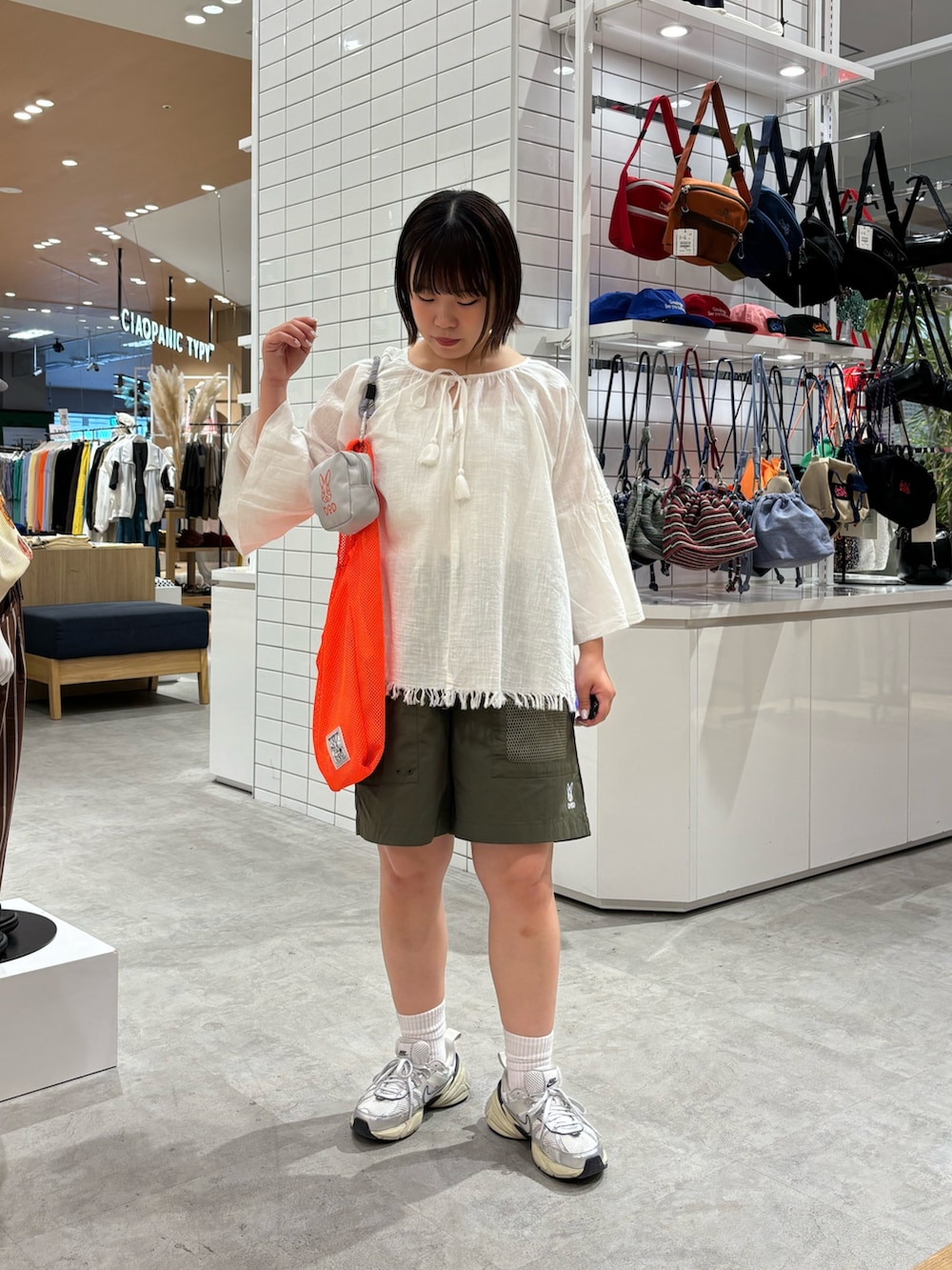 ホワイト系のシャツ/ブラウス、オレンジ系のトートバッグ、グリーン系のその他パンツを着用したレディースの春コーディネートの2枚目の写真