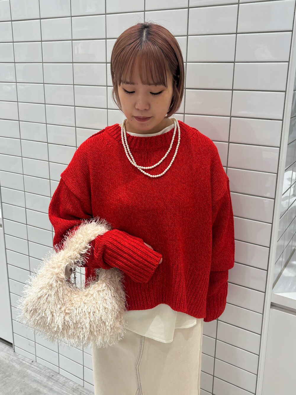 レッド系のニット/セーター、ホワイト系のTシャツ/カットソー、ホワイト系のデニムスカートを着用したレディースの秋コーディネートの5枚目の写真