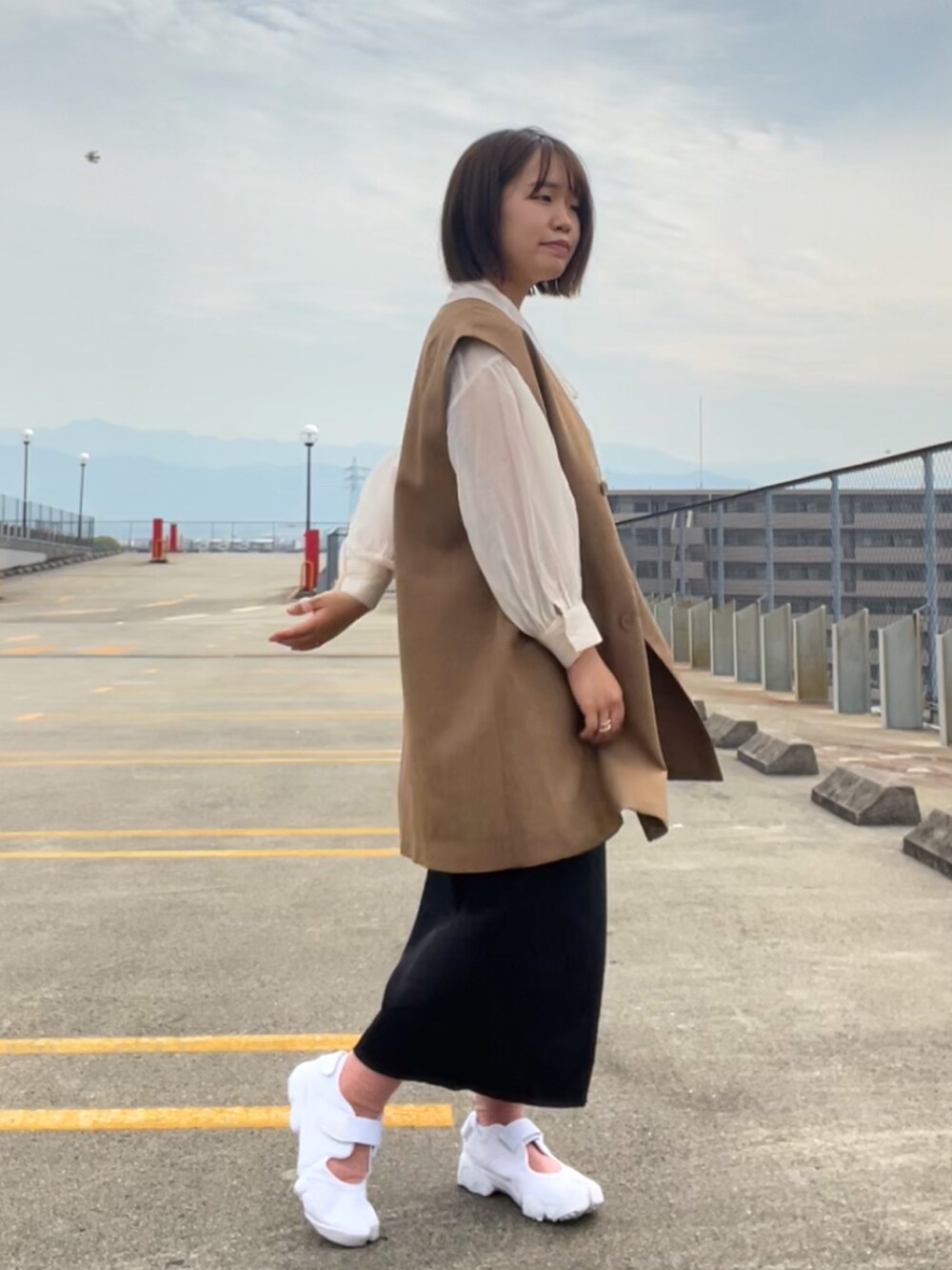 ホワイト系のシャツ/ブラウス、ブラウン系のベスト、ブラック系のスカートを着用したレディースの春コーディネートの2枚目の写真