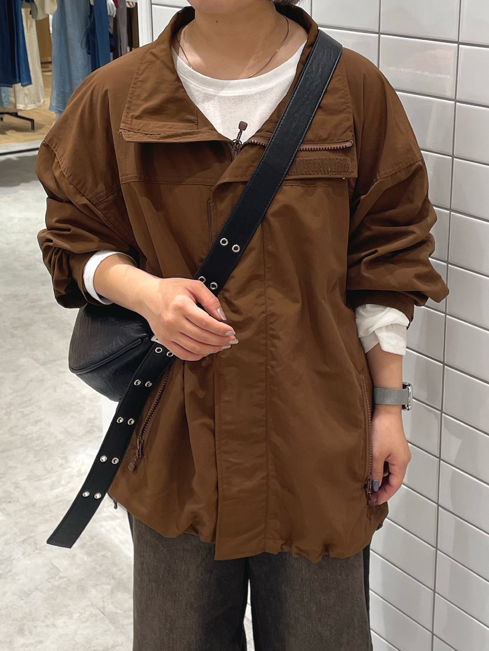 ブラウン系のナイロンジャケット、ブラック系のショルダーバッグ、ブラウン系のデニムパンツを着用したレディースの秋コーディネートの3枚目の写真