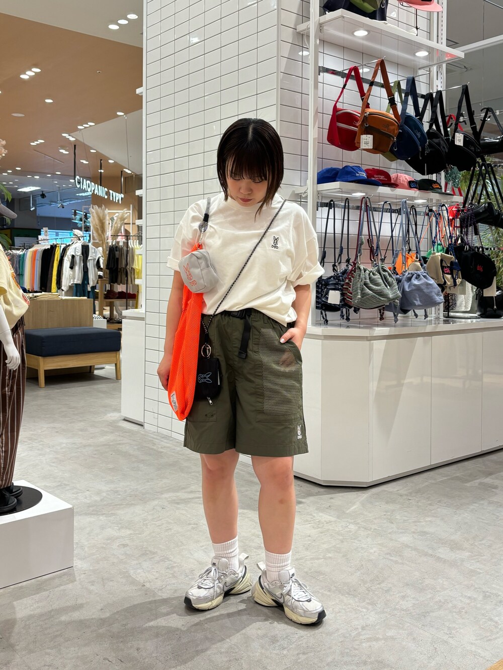 オレンジ系のトートバッグ、ホワイト系のTシャツ/カットソー、グリーン系のその他パンツを着用したレディースの春コーディネートの2枚目の写真