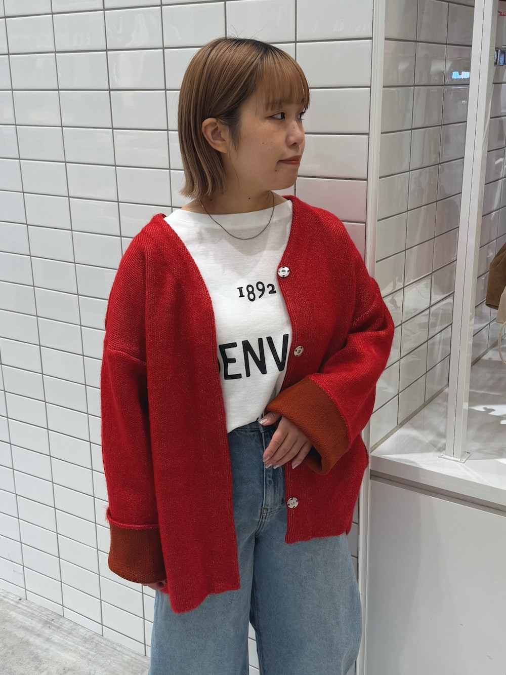 レッド系のカーディガン/ボレロ、ホワイト系のTシャツ/カットソー、ブルー系のデニムパンツを着用したレディースの春コーディネートの4枚目の写真