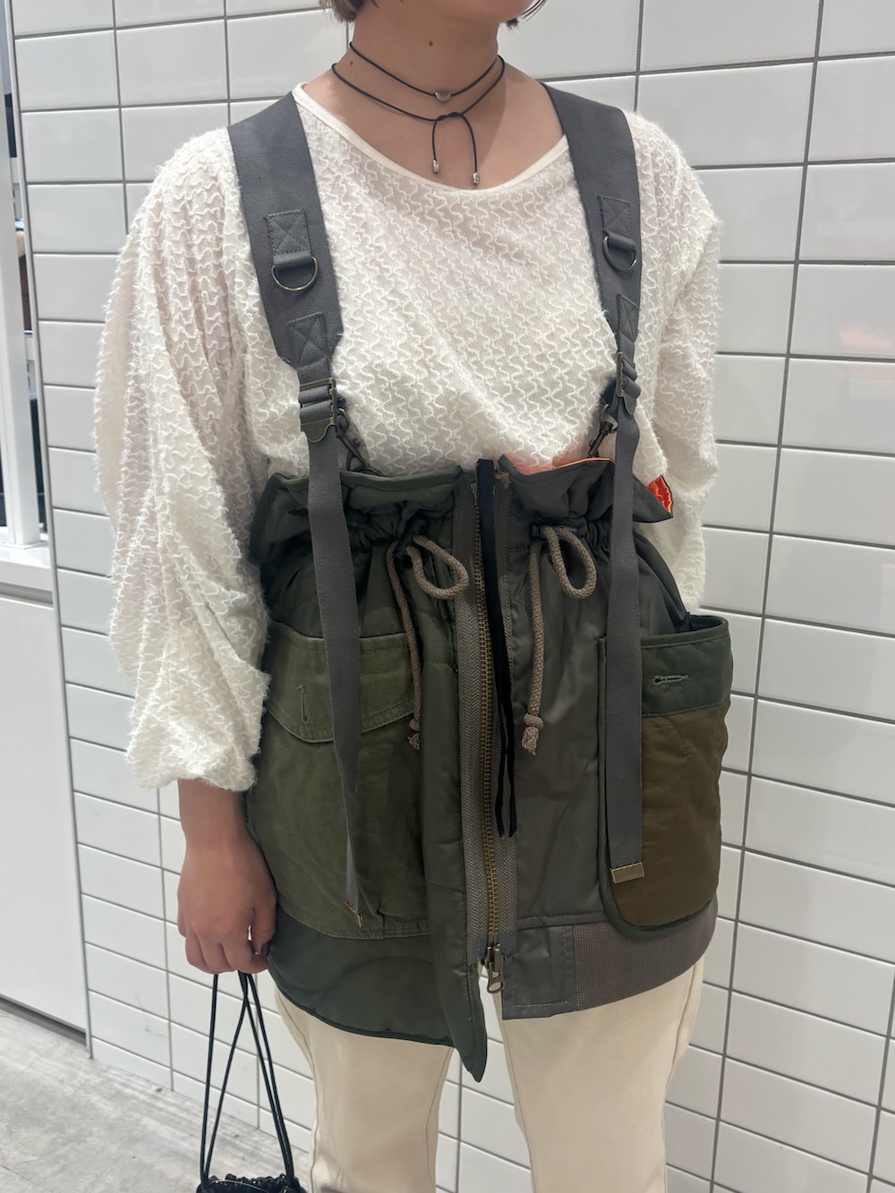 ホワイト系のTシャツ/カットソー、グリーン系のベスト、ブラック系のトートバッグを着用したレディースの秋コーディネートの3枚目の写真