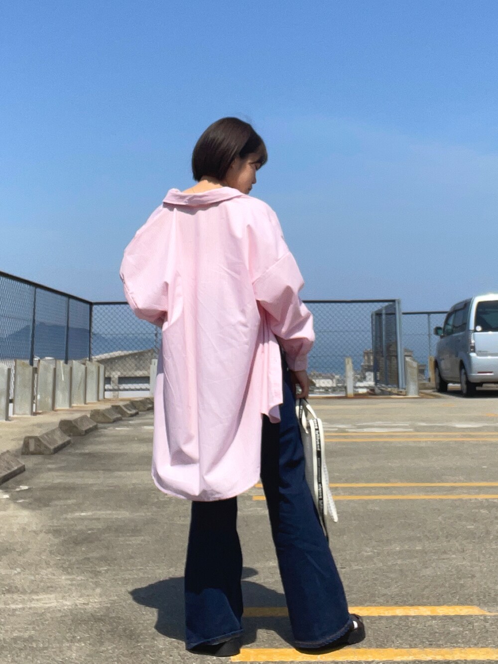 ホワイト系のタンクトップ、ピンク系のシャツ/ブラウス、ブルー系のデニムパンツを着用したレディースの春コーディネートの4枚目の写真