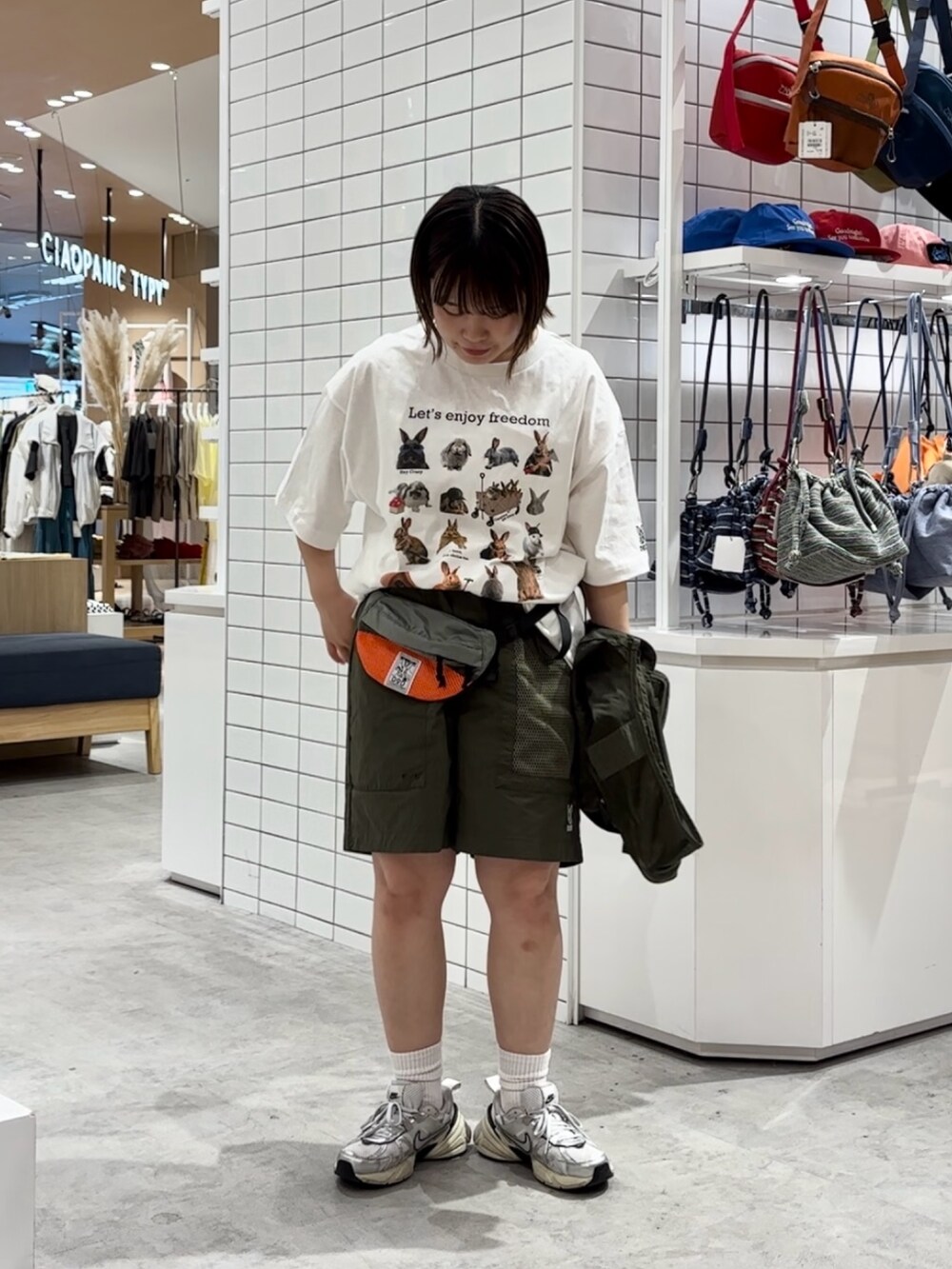 ホワイト系のTシャツ/カットソー、グリーン系のベスト、グレー系のトートバッグを着用したレディースの春コーディネートの3枚目の写真