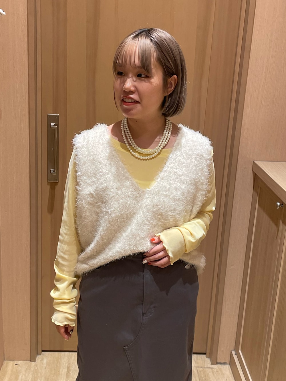 ブラック系のブーツ、グレー系のスカート、ホワイト系のベストを着用したレディースの秋コーディネートの4枚目の写真