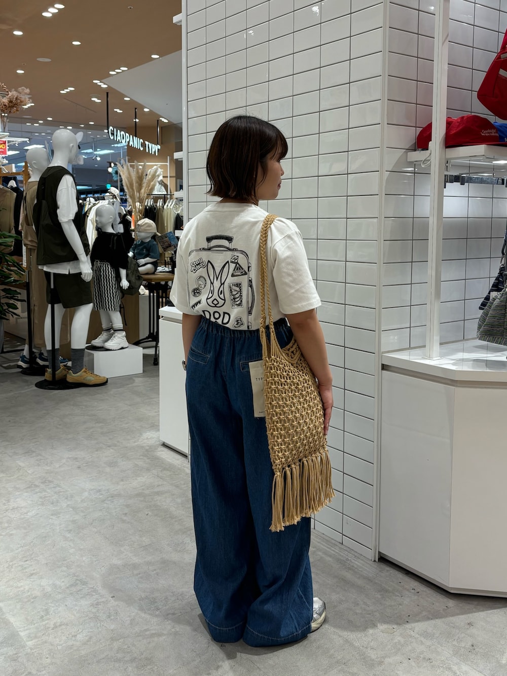 ホワイト系のTシャツ/カットソー、ブルー系のデニムパンツ、ベージュ系のトートバッグを着用したレディースの夏コーディネートの2枚目の写真