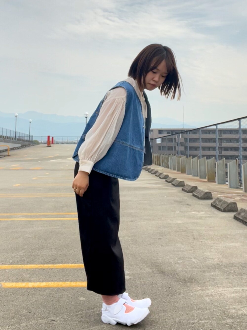 ホワイト系のシャツ/ブラウス、ブルー系のベスト、ブラック系のスカートを着用したレディースの春コーディネートの2枚目の写真