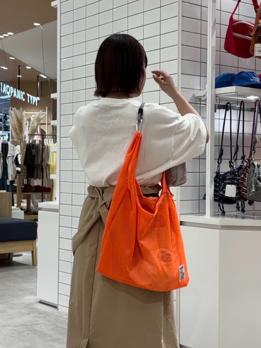 ホワイト系のTシャツ/カットソー、ベージュ系のスカート、オレンジ系のトートバッグを着用したレディースの春コーディネートの3枚目の写真